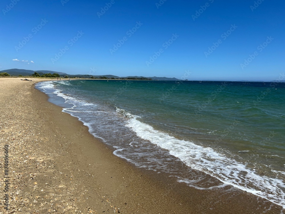 Serene beach with a clear blue sky and gentle waves on a sunny day Serene beach with a clear blue sky and gentle waves on a sunny day