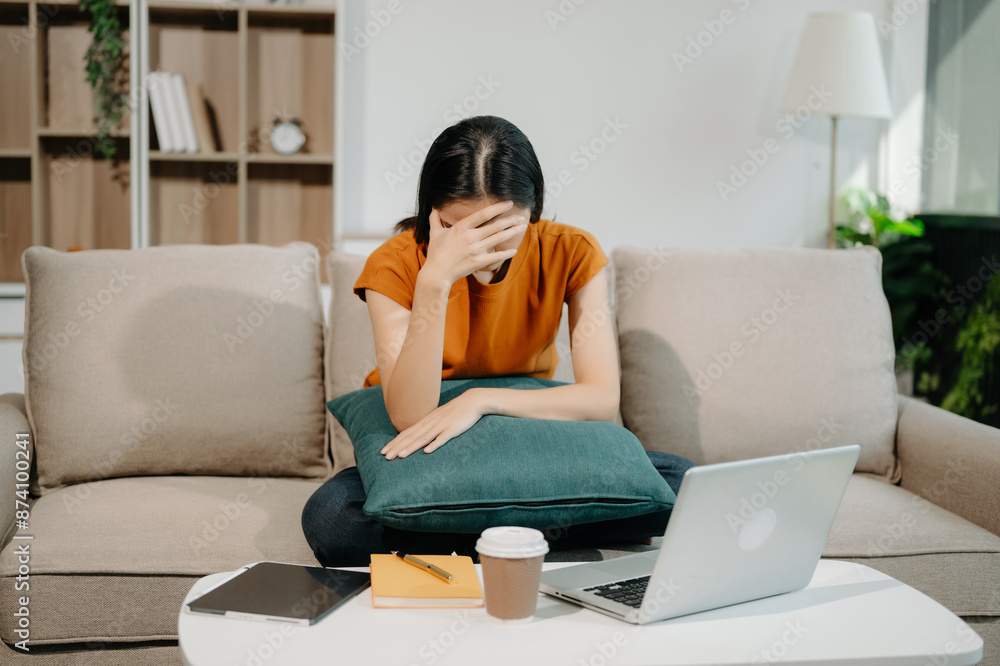 Woman who is tired and overthinking from working with tablet and laptop on sofaat home office.. Woman who is tired and overthinking from working with tablet and laptop on sofaat home office..