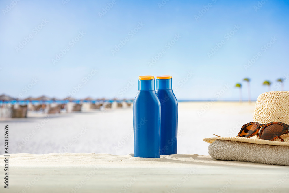 Blue containers for sun tan lotion and sunscreen oils on a bright table with tropical beach and a sea and clear sky background. Blue containers for sun tan lotion and sunscreen oils on a bright table with tropical beach and a sea and clear sky background.