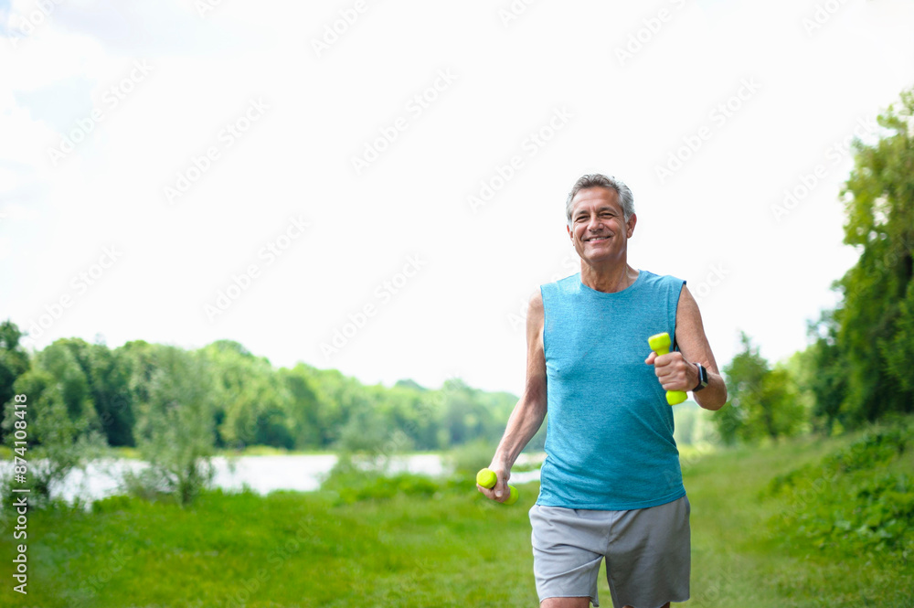 Sporty spirited man jogging with dumbbells in public park Sporty spirited man jogging with dumbbells in public park