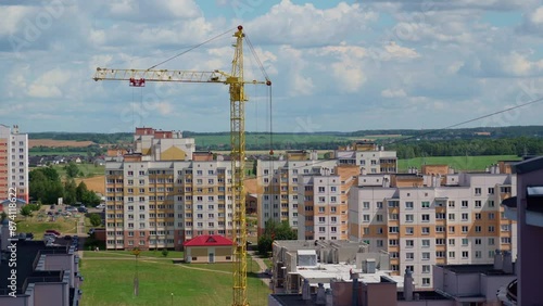 Working crane on construction set of building with heavy house panel on it. Sunny Day. Field At The Background