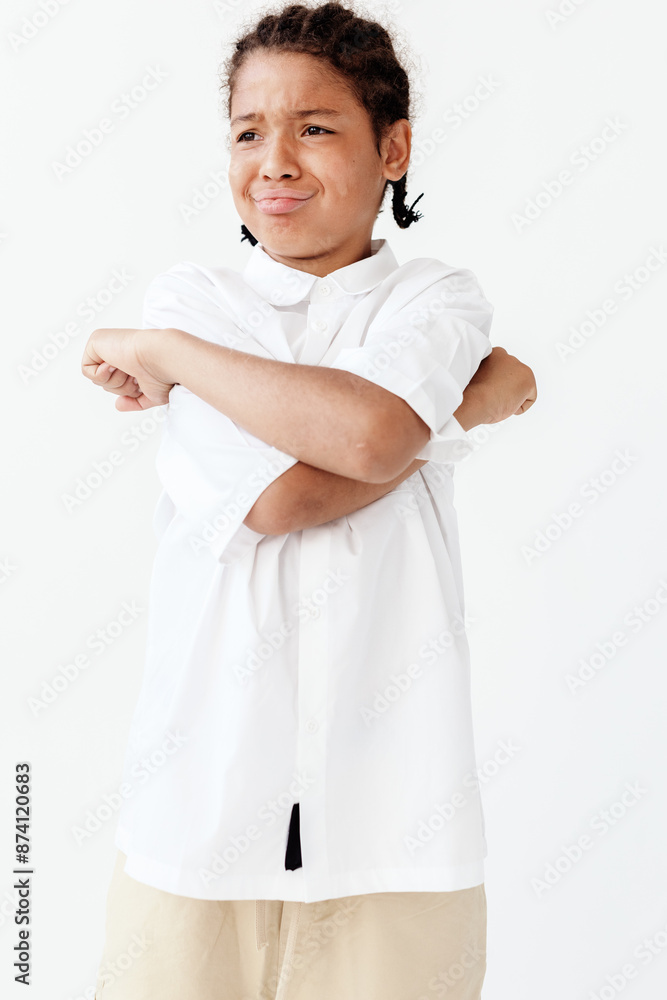 Confident young boy standing with arms crossed in trendy white shirt and khaki pants Confident young boy standing with arms crossed in trendy white shirt and khaki pants