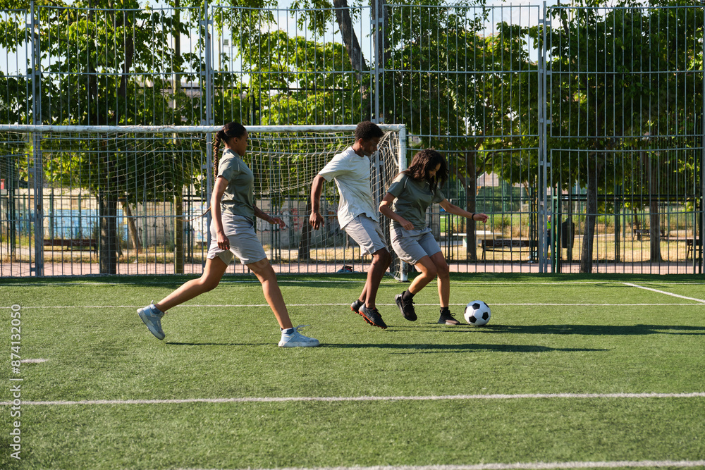 Three young soccer players are running on artificial turf during training session