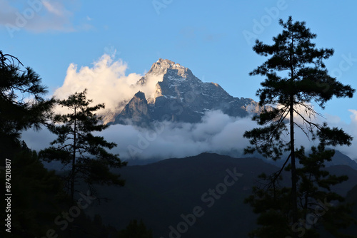 The peak of Mount Khumbila at sunset, view between the trees from the monastery of Monjo, Manjo village, Mount Everest Basecamp Trek, EBC, Nepal photo