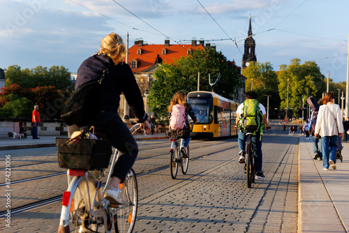 Scenic Dresden cityscape may people riding bikes tram crossing Augustus bridge Elbe river Holy Trinity church Cathedral sunset background. Healthy lifestyle Europe city Germany Saxony capital trip photo