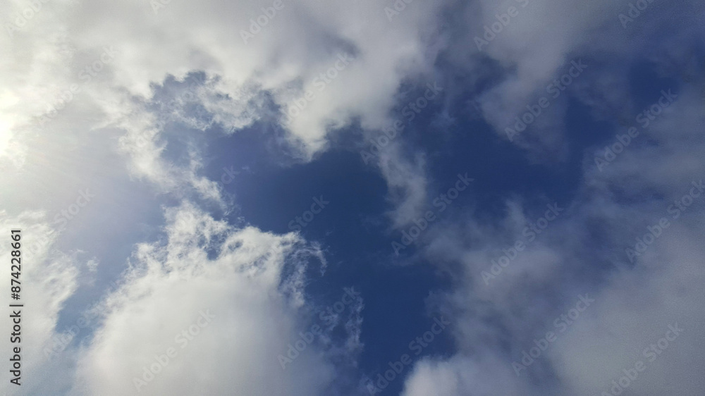 Fototapeta premium Sun shining through the clouds in a deep blue sky