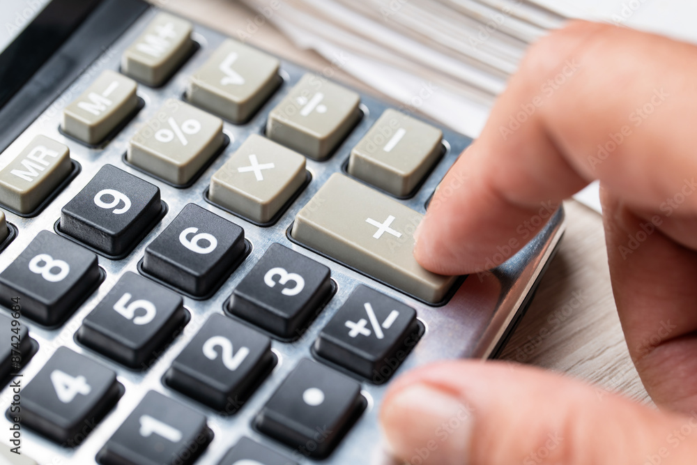 Closeup finger press at the adding button on a calculator