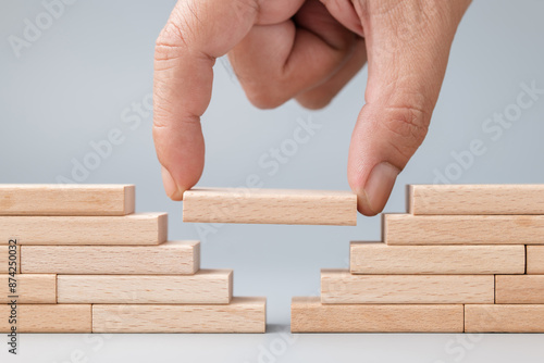 Tableau sur toile Closeup hand put a wooden piece between the gap of the wall built with wood toy,