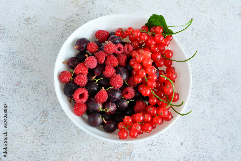 a bowl of raspberries, gooseberries and red currant top view a bowl of raspberries, gooseberries and red currant top view