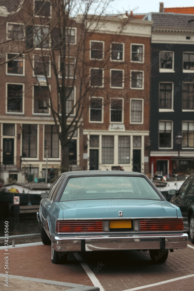 A classic blue car parked along a picturesque canal in Amsterdam, showcasing the city's historic architecture and charming urban landscape. This image captures the essence of Amsterdam's A classic blue car parked along a picturesque canal in Amsterdam, showcasing the city's historic architecture and charming urban landscape. This image captures the essence of Amsterdam's