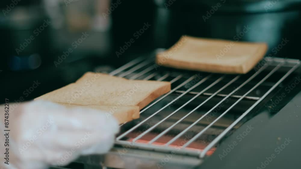 A hand toasting breads using a gas roaster with bokeh foreground and background A hand toasting breads using a gas roaster with bokeh foreground and background
