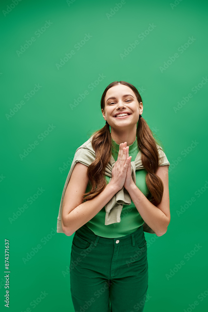 A young beautiful woman in her 20s standing in front of a vibrant green background in a studio setting.