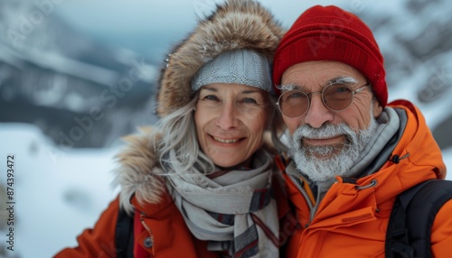  Portrait of old elderly couple at top of snowy mountain for winter sports holidays 