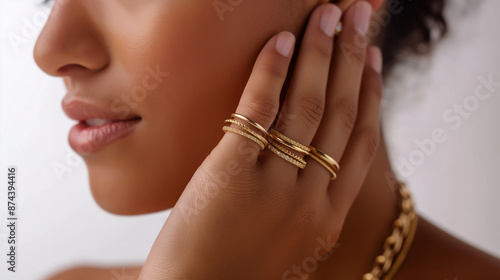 A woman wearing three gold bracelets on her wrist, with one bracelet made of thin chain and the other two wrapped around each hand in a delicate pattern.