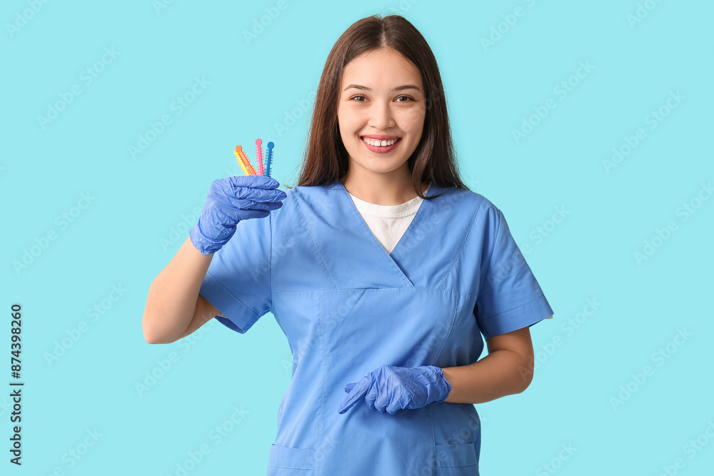 Young female dentist with elastic orthodontic braces on blue background Young female dentist with elastic orthodontic braces on blue background