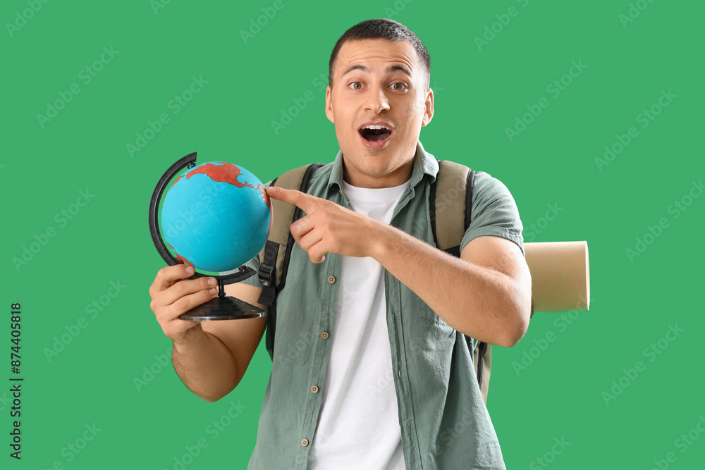 Surprised male tourist with globe on green background Surprised male tourist with globe on green background