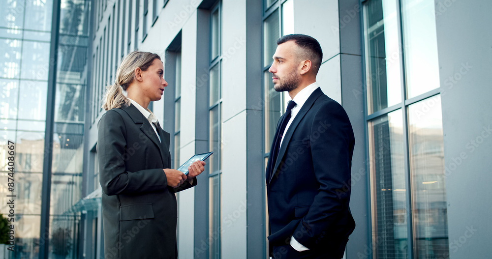 Portrait of two managers wearing business suits talk to each other in business center. Business people have serious conversation at work. Caucasians discuss next business meeting with partners. Portrait of two managers wearing business suits talk to each other in business center. Business people have serious conversation at work. Caucasians discuss next business meeting with partners.