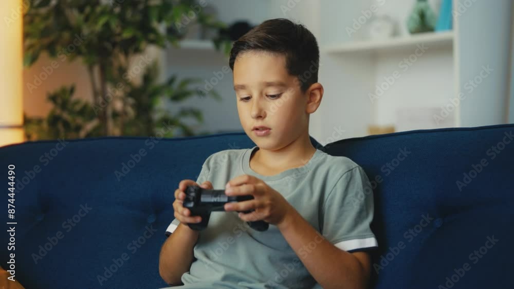 Focused young boy playing video game at home using gamepad, gaming hobby Focused young boy playing video game at home using gamepad, gaming hobby