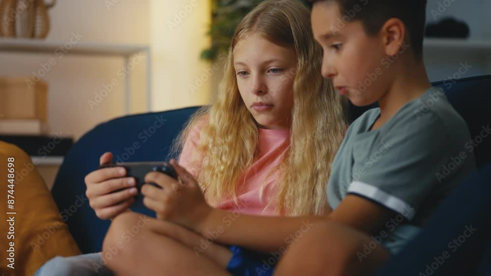 Young brother and sister watching a movie on phone, leisure time at home Young brother and sister watching a movie on phone, leisure time at home