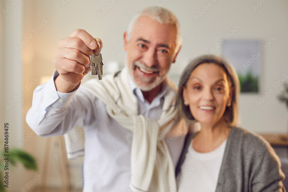 Happy elderly couple holding keys to new home fresh chapter in their lives. Senior couple wife nd husband holding keys to new home smiling together celebrate investment holding keys to new home Happy elderly couple holding keys to new home fresh chapter in their lives. Senior couple wife nd husband holding keys to new home smiling together celebrate investment holding keys to new home