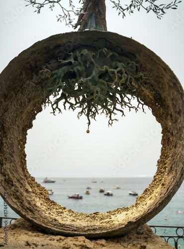 Obraz na płótnie View of bunch of boats floating on a sea through a metal round circle with tree roots located in Amalfi town, Italy, Street art monument, Koi no Yokan aka premonition of love overlooking Amalfi Sea w salonie