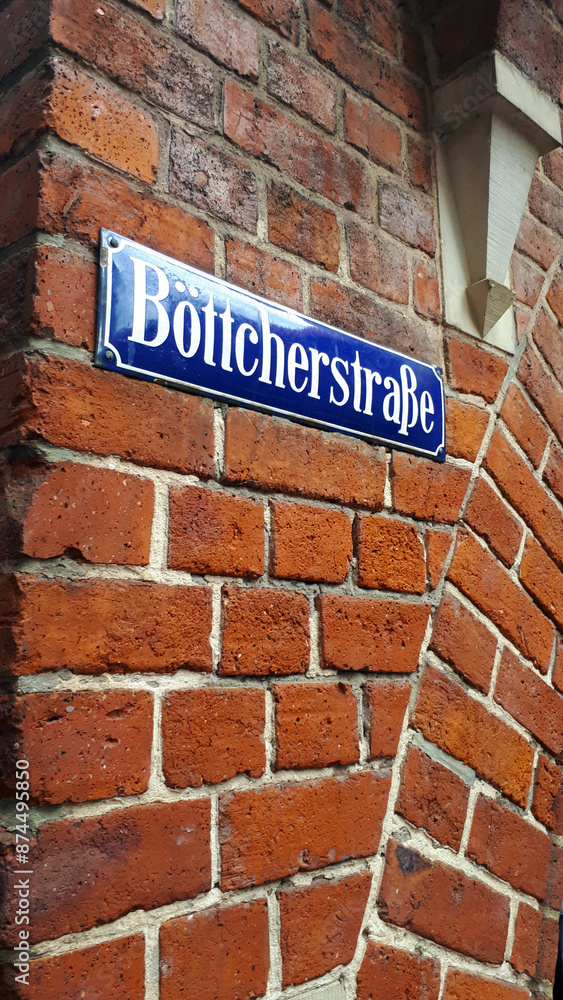 Obraz premium Blue german street sign with white letters indicating Boticherstraße on a red brick wall