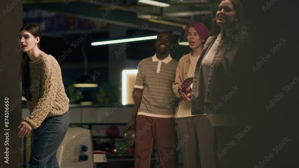 Full shot of two diverse guys supporting their girlfriends while having double date in bowling alley on weekend Full shot of two diverse guys supporting their girlfriends while having double date in bowling alley on weekend