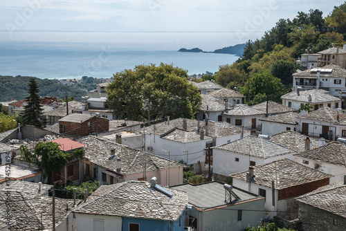 A view of the stone roofs and close-knit houses of the village of Panagia on the island of Thassos. The sea can be seen in the distance. photo