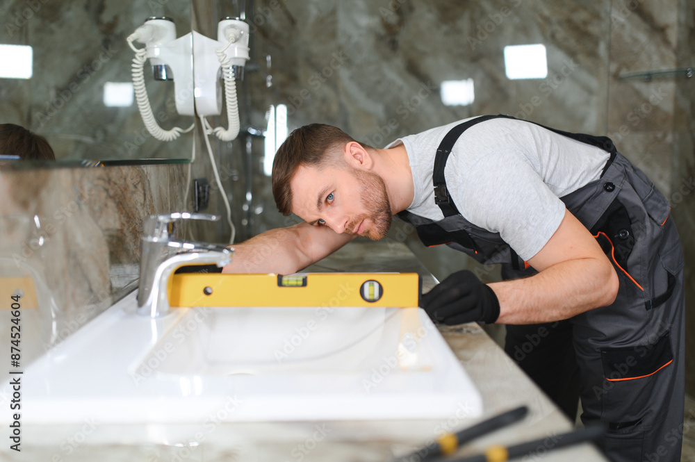 Plumber install sink in bathroom, checks even level of installation. Concept repair service plumbing Plumber install sink in bathroom, checks even level of installation. Concept repair service plumbing