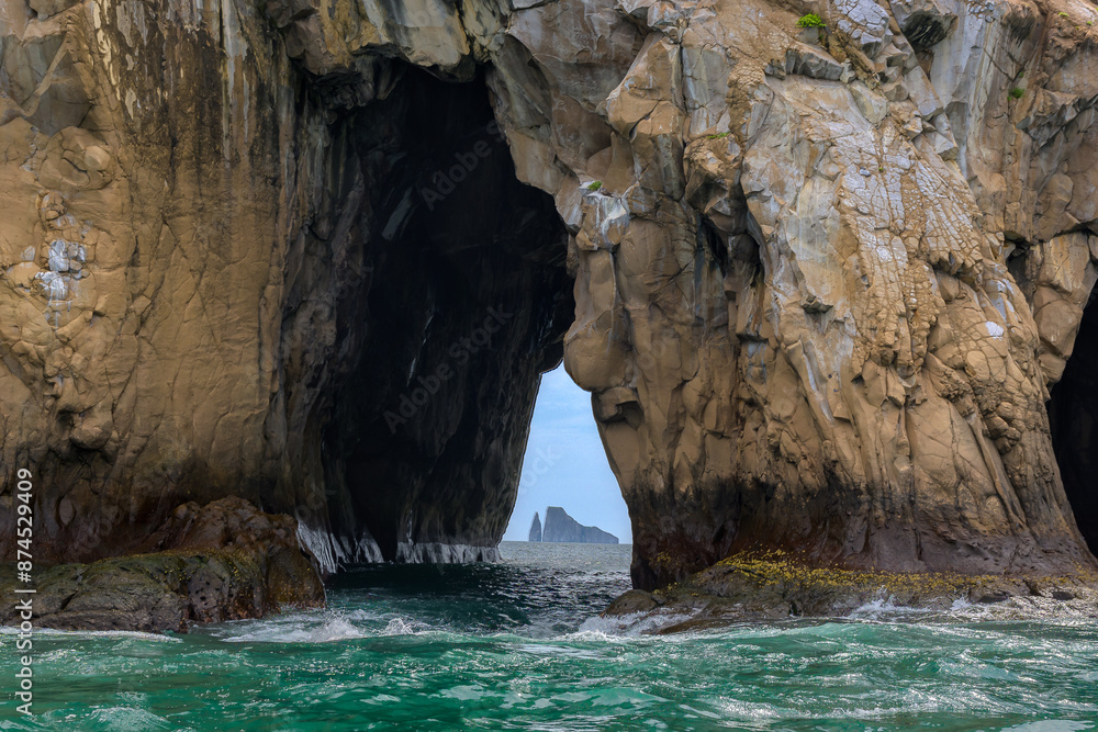 Fototapeta premium Roca enmarcada en túnel de otra roca en el mar - Kiccker rock (león dormido) enmarcado en túnel de cerro brujo - Isla San Cristóbal - Islas Galápagos - Ecuador