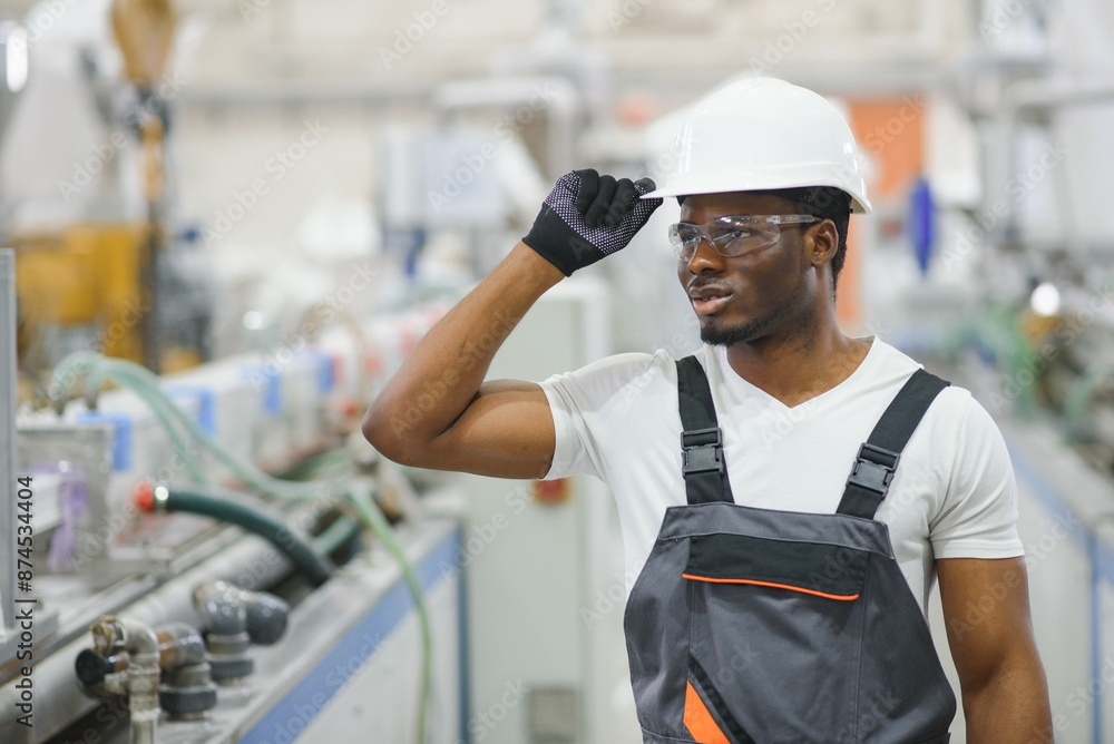 Professional Heavy Industry Engineer Worker Wearing Uniform, Glasses and Hard Hat in a Factory Professional Heavy Industry Engineer Worker Wearing Uniform, Glasses and Hard Hat in a Factory