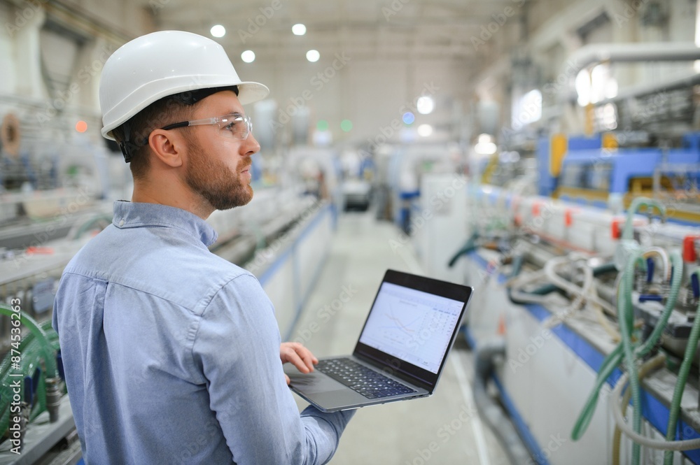 Engineer in hardhat is using a laptop in a heavy industry factory Engineer in hardhat is using a laptop in a heavy industry factory