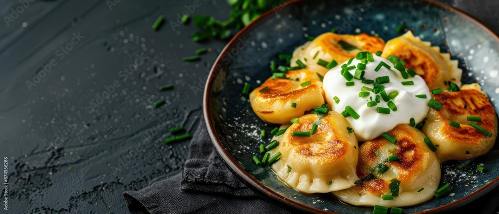 A serving of pierogi filled with cheese and potatoes, topped with sour cream and chives for a Polish delight with copy space A serving of pierogi filled with cheese and potatoes, topped with sour cream and chives for a Polish delight with copy space