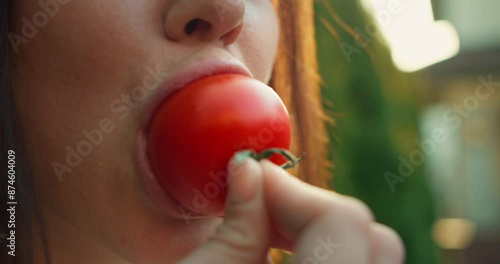 Wallpaper Mural Close-up of a brunette girl biting a red tomato in the yard of her house on a sunny day during a weekend barbecue Torontodigital.ca