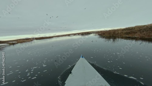 Kayaking down a frozen river in the Arctic with melting ice and overcast skies overhead