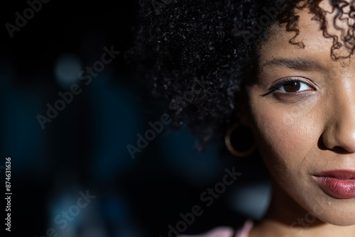 Close-up of woman with curly hair and hoop earring, looking confidently, copy space