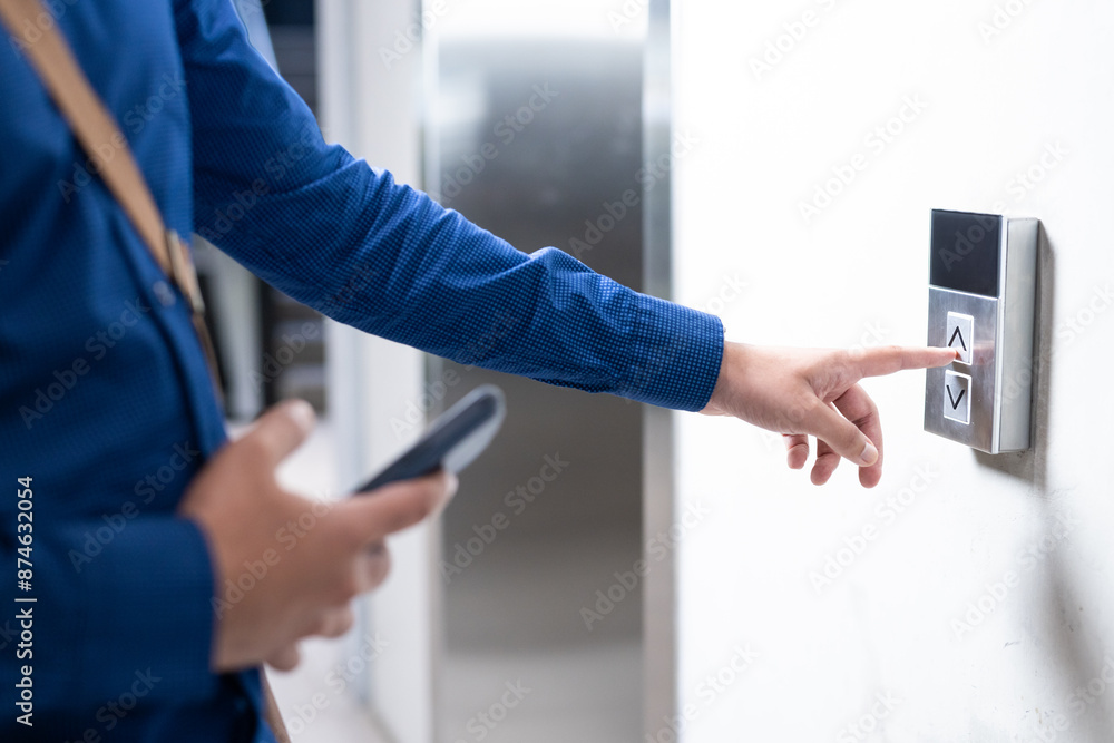 Naklejka premium Pressing elevator button, person holding smartphone and waiting in office building
