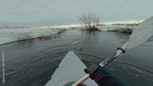A lone kayak navigates a river in a snowy landscape