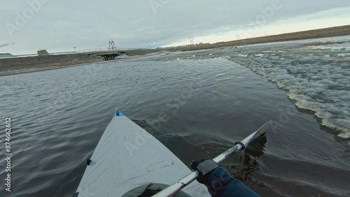 A kayaker navigates through icy waters in a vast arctic landscape. The scene captures the challenge and beauty of kayaking in a cold and remote environment.