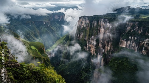 A scenic mountain range with towering cliffs and lush green valleys, shrouded in low-hanging clouds.
