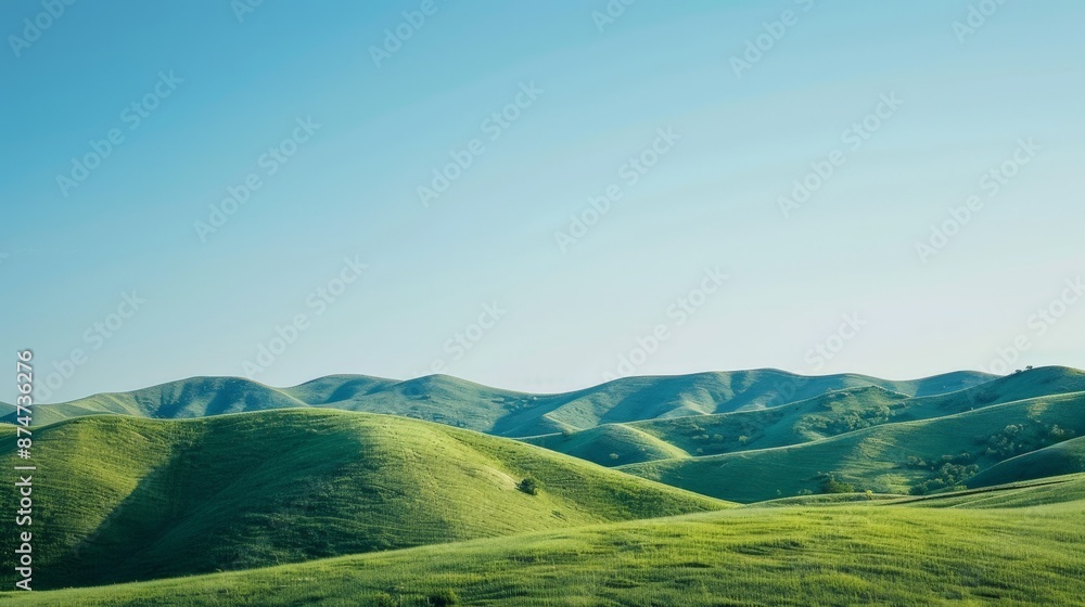 Obraz premium A serene landscape background featuring rolling hills under a clear blue sky, perfect for creating a peaceful and calming atmosphere.
