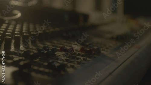 Technician moves levers up on equalizer console in semi-dark studio closeup. Producer processes tracks on control panel. Making music photo