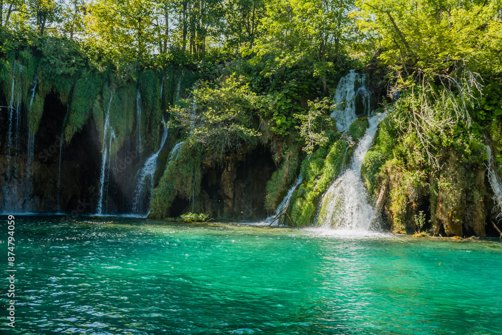 Fototapeta premium Vibrant scene of multiple waterfalls cascading into turquoise waters surrounded by lush greenery, in Croatia