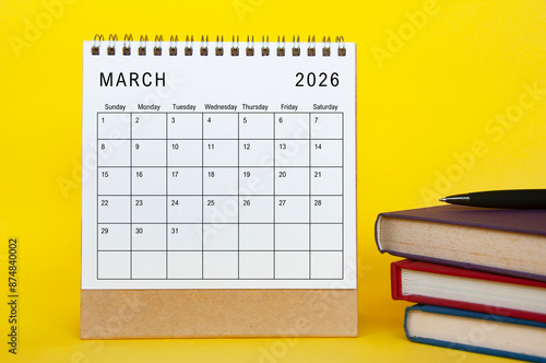 March 2026 calendar with yellow cover background and books. New month and calendar concept. photo