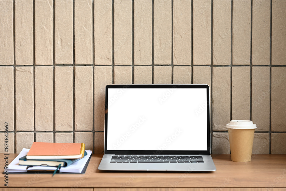 Laptop with empty display, documents and paper cup of coffee on wooden table in modern office Laptop with empty display, documents and paper cup of coffee on wooden table in modern office
