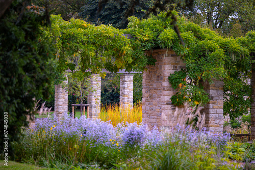 A beautiful park landscape with a stone brick pavilion and blooming plants. Autumn scenery of Nordpark, Dusseldorf, Germany. photo