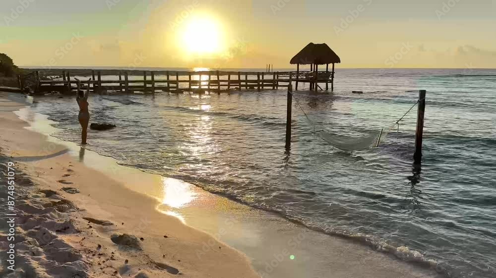 Sexy young woman practicing yoga, which is a sport of relaxation and meditation in a beautiful orange sunrise over the crystal clear turquoise waters of the Caribbean Sea, is a healthy lifestyle.