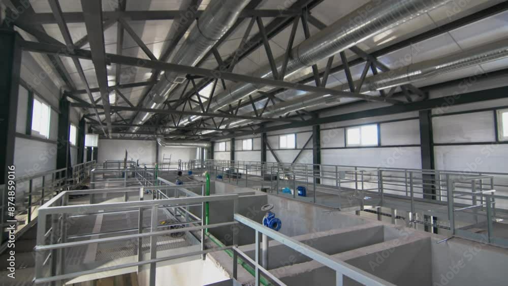 Well-lit workshop with windows houses liquid tanks divided by concrete partitions. Basins for sedimenting wastewater. Inside look at plant operations Well-lit workshop with windows houses liquid tanks divided by concrete partitions. Basins for sedimenting wastewater. Inside look at plant operations
