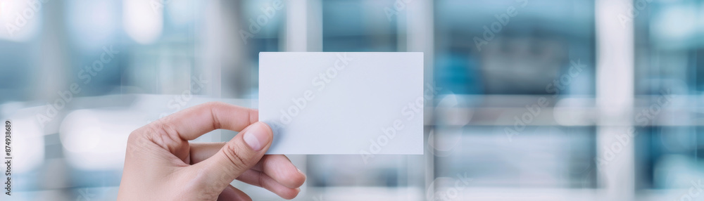 Mockup of a business card held between fingers, with a blurred office background, ideal for branding purposes. Mockup of a business card held between fingers, with a blurred office background, ideal for branding purposes.