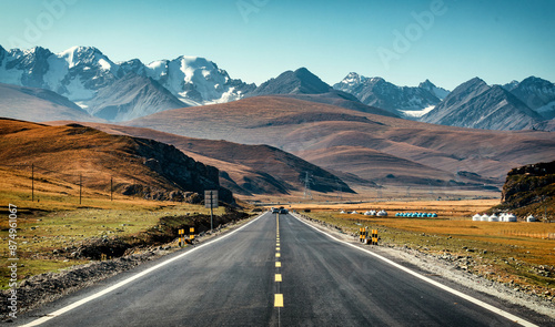 Quadro su tela Duku Highway extending in grassland snow-capped mountains in the autumn in Xinji